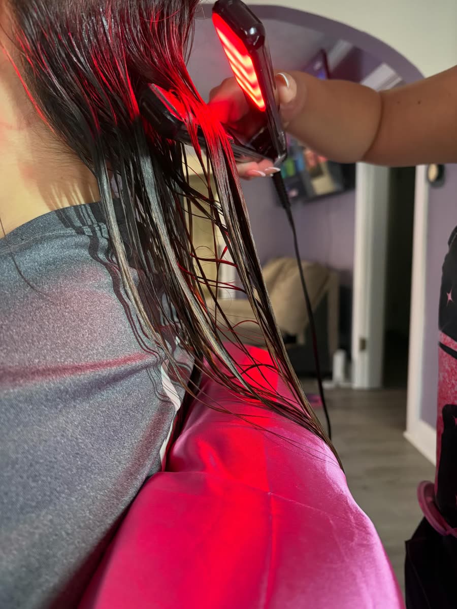 Aplicación del tratamiento con plancha de luz roja sobre el cabello húmedo.